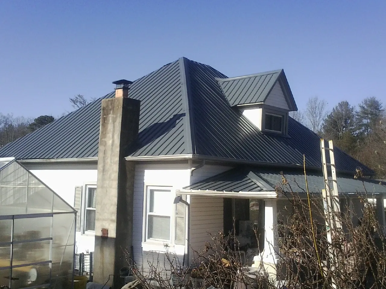 Dark blue standing seam metal roof on a white farmhouse with dormer — Slate & Tile Roof Repair by Roofing Brothers in Franconia