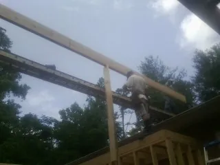 Carpenter setting a ridge beam over a new addition frame — Ice Dam Removal by Roofing Brothers in Franconia