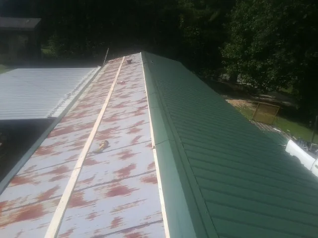 Old rusted panels beside newly installed green metal roofing — Wind Damage Roof Repair by Roofing Brothers in Franconia