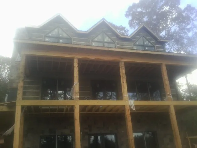 Dormers and porch framing on a large log home under construction — Roof Coating work by our crew in Franconia