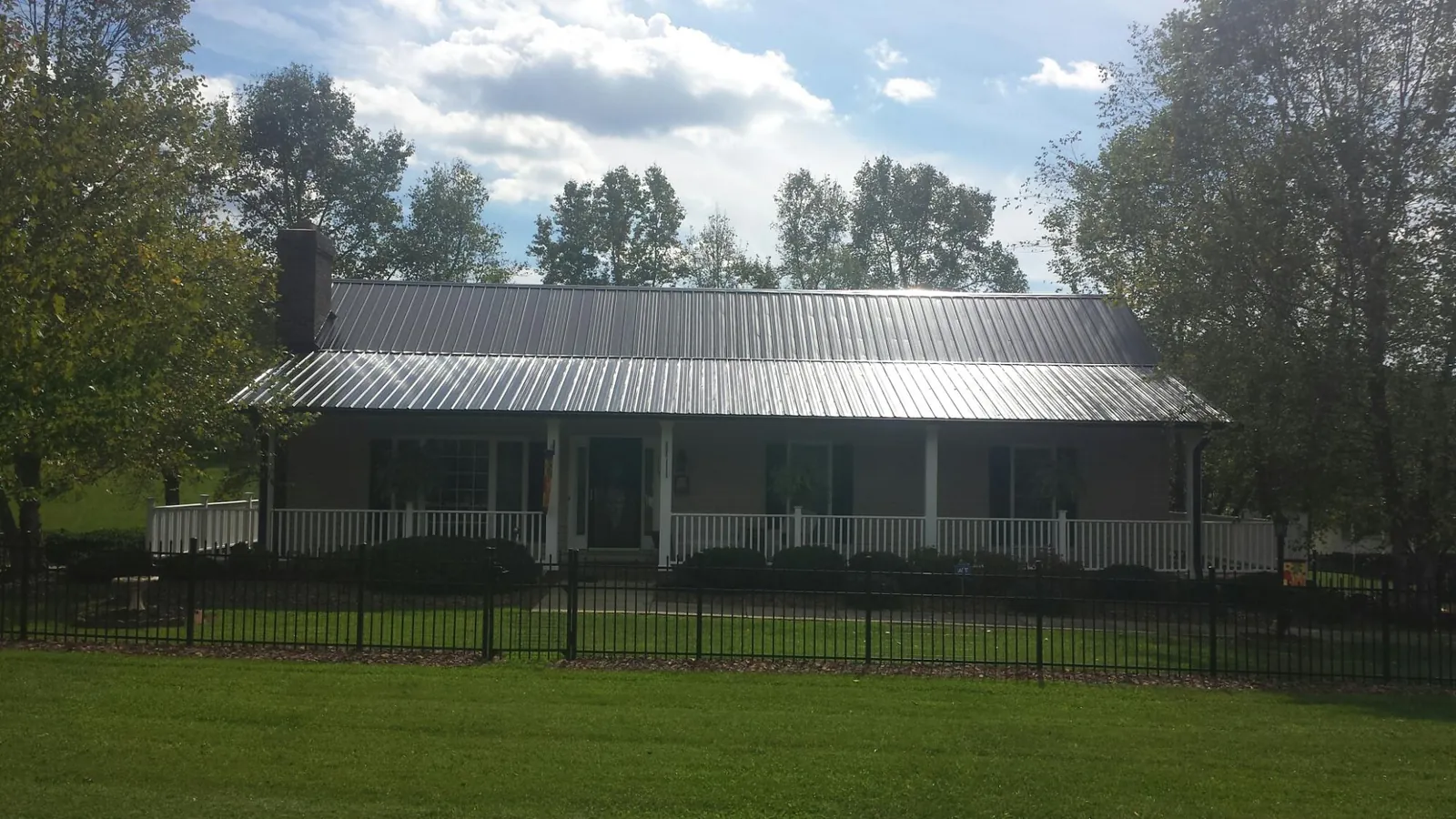 Gray metal roof on a brick ranch with a full width front porch — Gutter Guard Installation work by our crew in Franconia