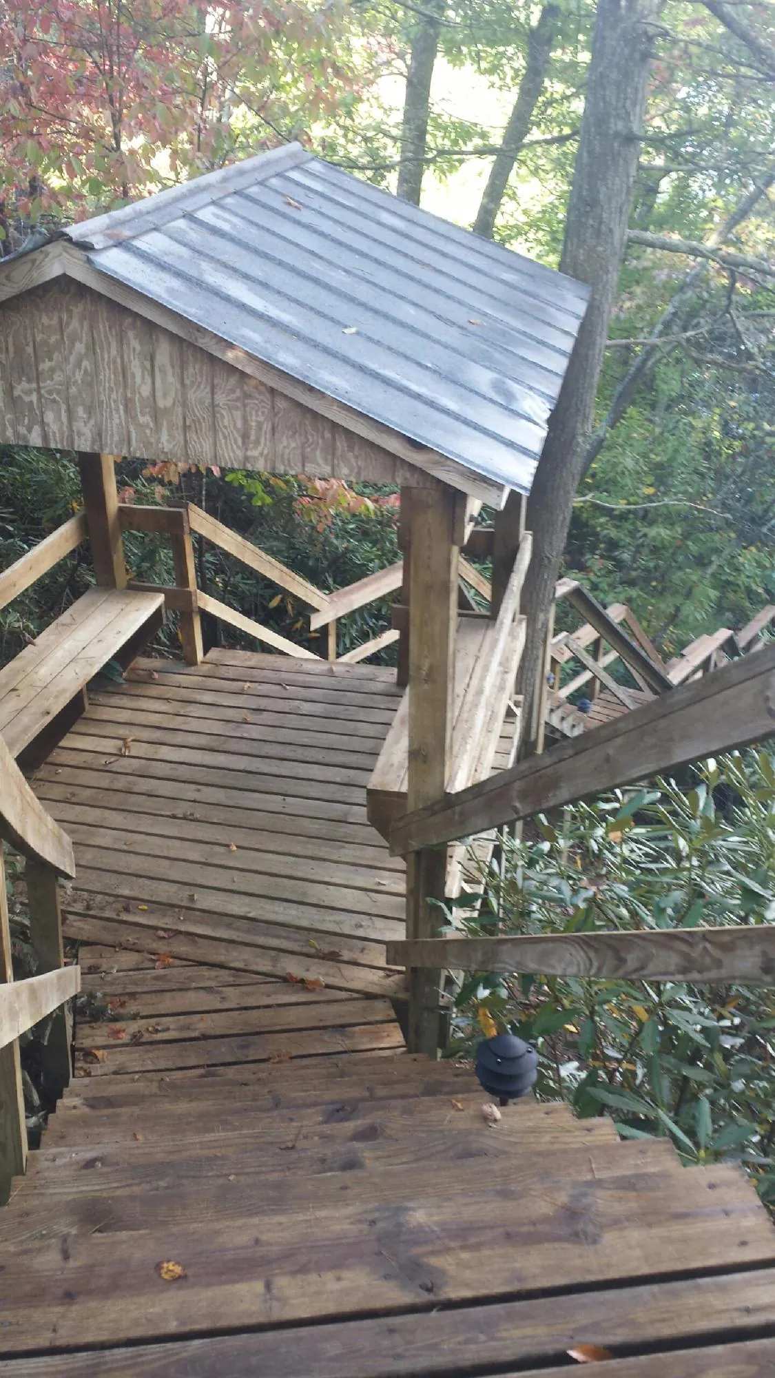 Metal roofed shelter over wooden steps on a wooded walkway — Skylight Repair & Installation work by our crew in Franconia