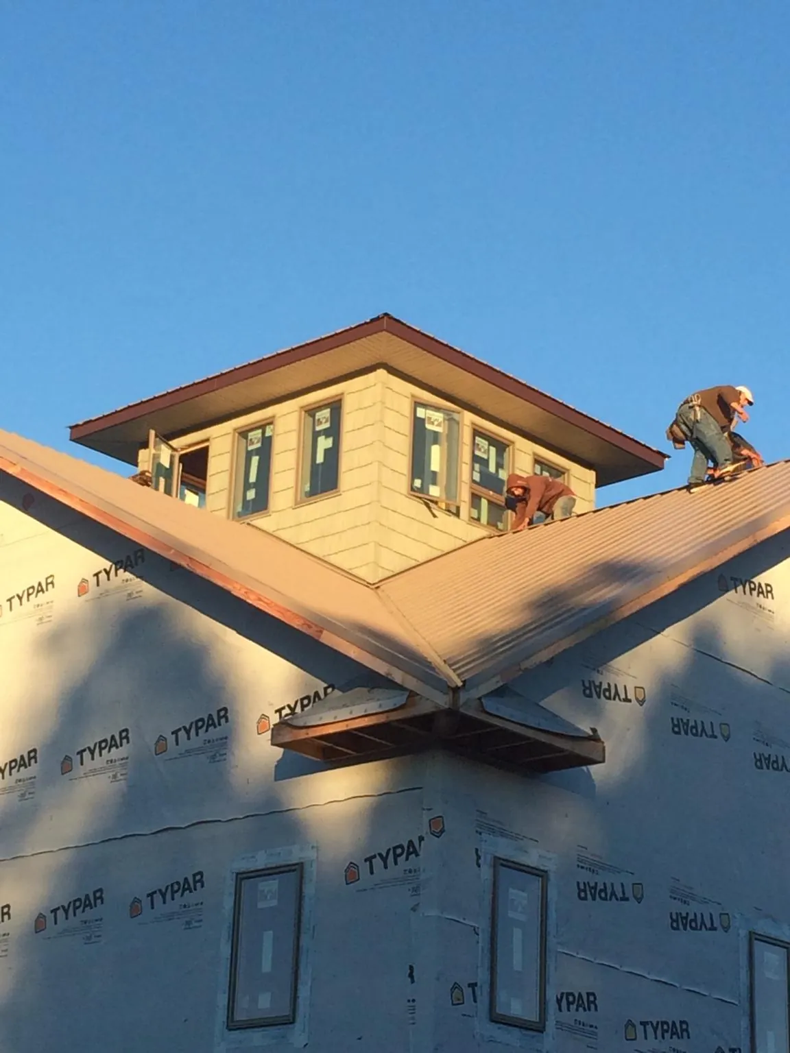 Roofers working around a rooftop cupola on a new metal roof at sunset — Roof Waterproofing in Franconia by Roofing Brothers
